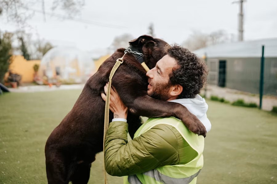 A Guayabo Animal Rescue team member holding a rescued dog standing up to hug him.